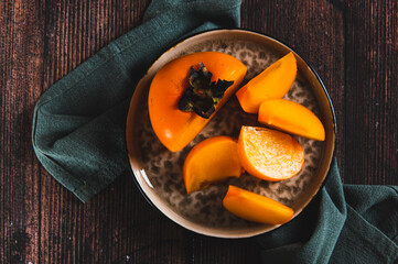Close up of fresh ripe sliced persimmon on a plate on the table top view