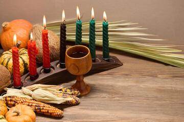 Kwanzaa Table Setting. A Kwanzaa display with lit candles, maize, and decorative pumpkins