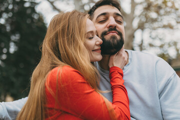 relaxed pair seated among colorful fall foliage, casual lovers share warmth amidst vibrant autumn...