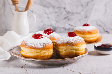 Sweet donuts in powdered sugar with jam on a plate on the table