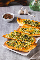Golden garlic bread with herbs on a plate on the table vertical view