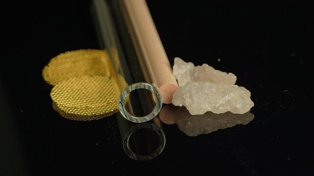 Crystal meth drug in rocks with smoking crack pipe on the table of addict. Addiction and drugs trafficking. Illicit drugs very potent and addictive, substances altered for street sale by drug dealer.