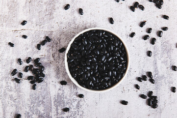 Close up of raw black beans in a bowl and in a spoon on the table top view