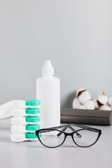 Concept of choosing between glasses and contact lenses on a table vertical view