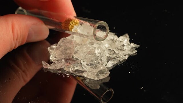 Crack cocaine drug in rocks or hard crystals with smoking crack pipe on the table. Illicit drugs very potent and addictive for sale in the streets and contribution to homelessness and addictioncrisis