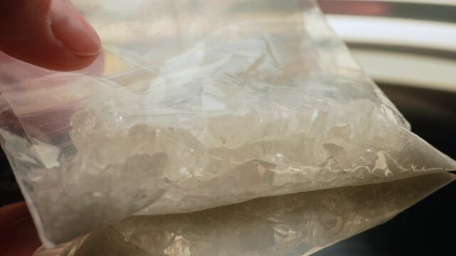 Methamphetamine drug in a plastic bag. Crystal meth or methamphetamine a recreational and highly potent and addictive drug. Crack cocaine in hard form of crystals. Addiction and drug trafficking.