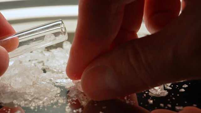 Placing crystals of drug in glass smoking pipe from harm reduction stem kit. Preparation for safe smoking or consumption of Fentanyl, Cocaine, Crystal meth or Crack Cocaine.