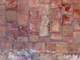 Weathered and eroded terracotta clay tiles texture floor. Unglazed ceramic tile, made of natural clay, handmade, rustic, mediterranean, warm red tone, for interior and exterior floors and walls. 