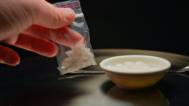 Drug dealer preparing and packaging Fentanyl Crystal meth or Crack Cocaine for sale and distribution. Drug trafficking and addiction crises. Crystals use in glass tube or stems and primarily smoking.