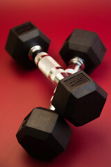 Hexagonal dumbbells with silver accents are positioned on a striking red surface, highlighting fitness gear ideal for strength training and enhancing workout sessions