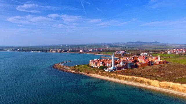Approaching sunny coast of the Black Sea in Bulgaria. View on the beautiful Aheloy Lighthouse and Marina Cape complex in Aheloy from drone.