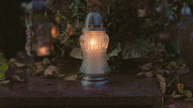 Front view of a lit memorial candle on a gravestone, symbolizing remembrance and contemplation