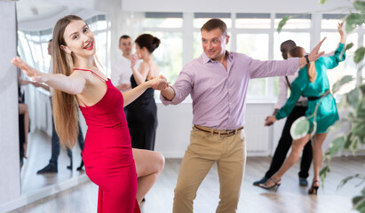 Fototapeta premium Woman paired with man practices movements of hali gali dance and trains to perform movements during lesson in choreography studio.