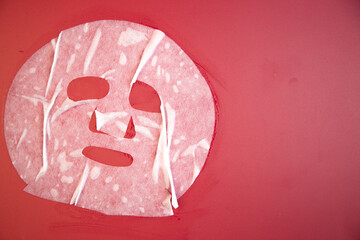 Soft facial mask on bright red background, highlighting skincare routine and beauty treatment, emphasizing relaxation and self-care in a visually appealing manner