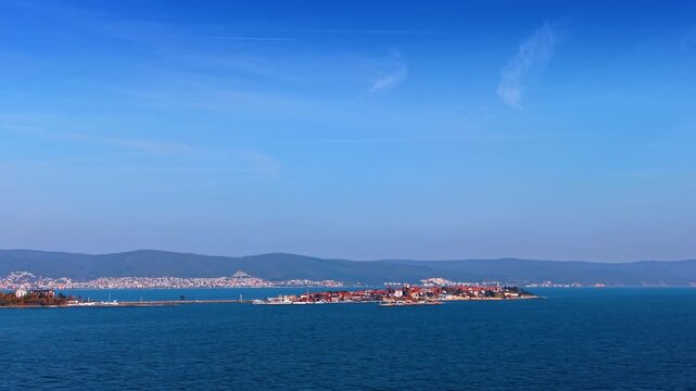 Picturesque cityscape locate don the shore of the Black Sea. Hazy mountain range at backdrop. Aerial view.