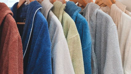 A row of clothes hanging on a rack, including a blue sweater. The clothes are of different colors...