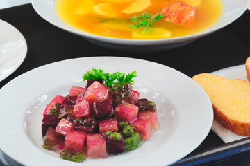 A plate of salad and a bowl of soup. The salad is garnished with beets and parsley. Lunch on a tray.