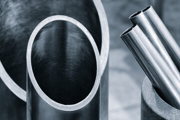 Vertical metal pipes cut diagonally by industrial cutting saw machine, metalworking industrial concept background