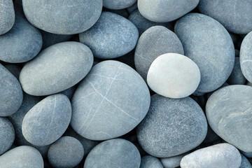 Pebbles stones on seashore as  texture background for design web banner template page. many stones and they are different in color and size dry stones illuminated by sun.