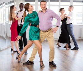 Naklejka premium With unhurried music, man with woman in couple spins to rhythm of waltz during lesson for novice students. Classes in mini-groups for those who want to learn dancing