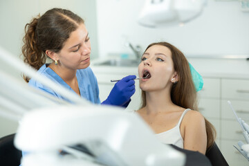 Female doctor checks young woman teeth during visit to a dental clinic