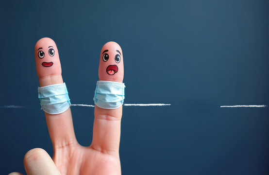 Two fingers wearing face masks with drawn eyes and mouths. Social distance concept during virus outbreak. Coronavirus prevention message. Awareness and health care topic.