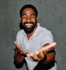 A portrait of young happy black man posing by  a gray wall in the street outdoors