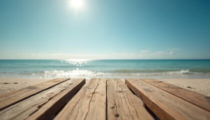 Fototapeta premium Wooden planks on sandy shore meet calm sea under bright sun. Beach backdrop for product display. Clear blue sky over ocean waves and waterline. Natural coastal setting.