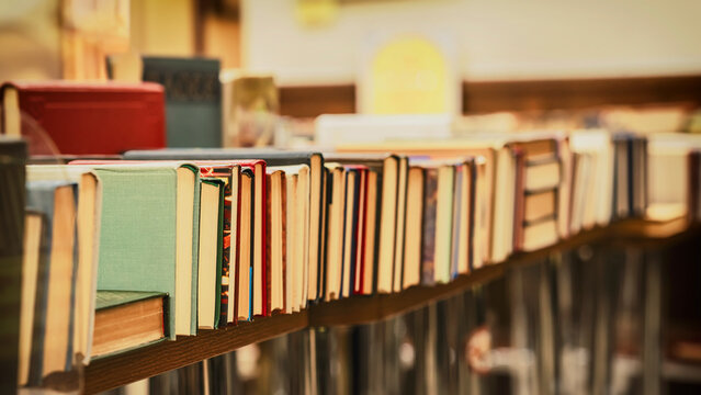 Pile of vintage books on table in store. Books arranged on wooden shelf with vintage look and shallow depth of field. Book collection, literature archive. Education, hobby, reading concept