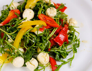 Fresh salad with arugula, mozzarella, tomatoes and avocado in a bowl. Healthy vegetarian dish. High quality photo