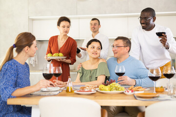 Happy companions congregated around a festive table, participating in animated discussions and enjoying the delights of red wine