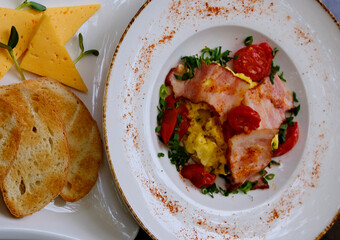Breakfast sandwich with fried egg, bacon and green sprouts on white background, top view, copy space. Fried sunny side egg with bacon on toast with microgreens and morning cappuccino.