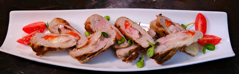 Cold appetizer, whole baked turkey and minced meat roll wrapped in bacon, on a black plate on a dark wooden background. Recipes for Thanksgiving, Christmas. High quality photo