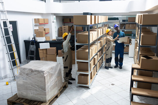 Staff performing manual labor tasks in a busy industrial warehouse, managing product dispatch, checking orders and organizing cargo for shipment in the logistics center activity.