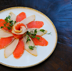 a large plate of sliced salmon and pieces of butterfish. Garnished with herbs and lemon slices. cold appetizer from valuable tasty species of marine fish. High quality photo