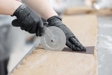 Chef using pizza cutter to shape croissant dough in bakery factory
