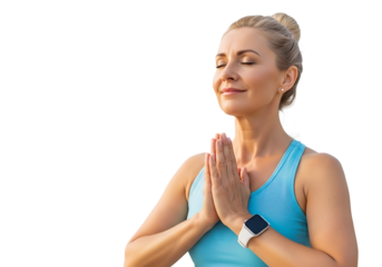 A serene, middle-aged woman with blonde hair in a bun meditates peacefully, eyes closed, hands in prayer pose at her heart. She wears a light blue tank top and a modern smartwatch, embodying calm mind