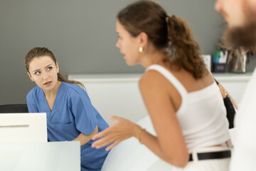 Obraz premium Dental clinic administrator talks to patients at the reception desk
