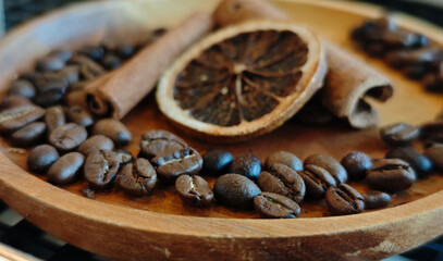 Coffee beans, cinnamon sticks, dried blood oranges on a wooden plate, herbs in a coffee shop.