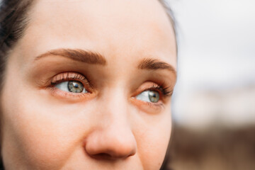close-up of a woman's eyes with green-blue irises, looking off to the side. This close-up shot...