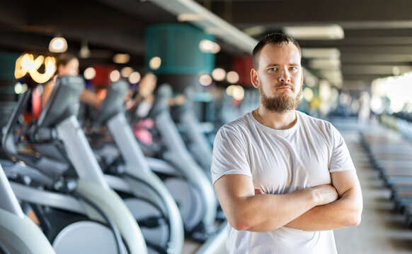 Young guy trainer in sportswear poses in middle of fitness center gym. Active lifestyle, daily workouts in crossfit gym