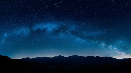 Brilliant celestial band arches over a dark mountainous horizon under a clear night sky