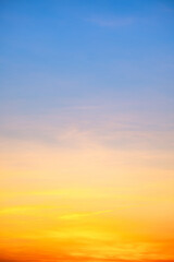 Sunset or sunrise sky with a vibrant gradient of orange, gold, and soft blue. Clear atmosphere with wispy clouds. Peaceful, natural light background. hope, freedom, new day Concepts, Vertical