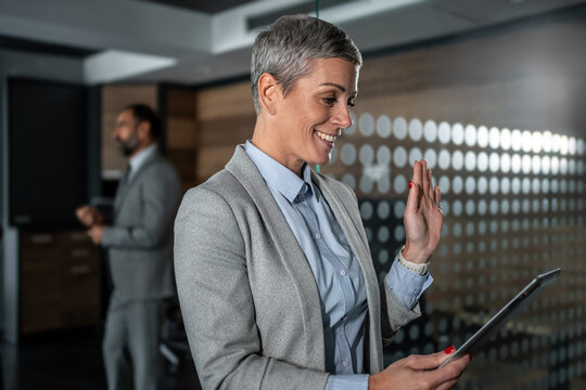 Businesswoman having video call on tablet waving hand