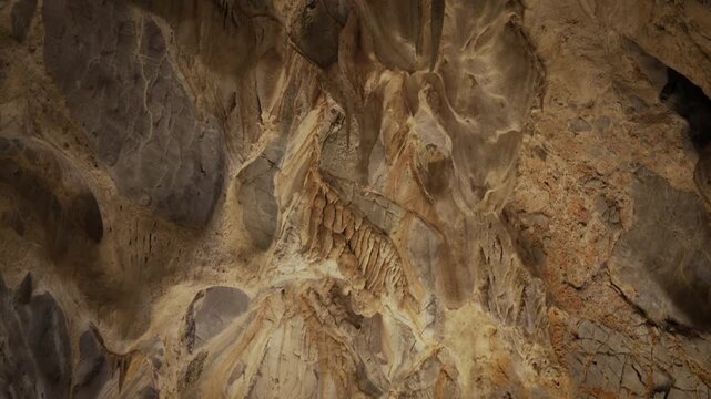 atural limestone cave texture with stalactites and stalagmites in darkness. Mysterious underground tunnel in Thailand.	

