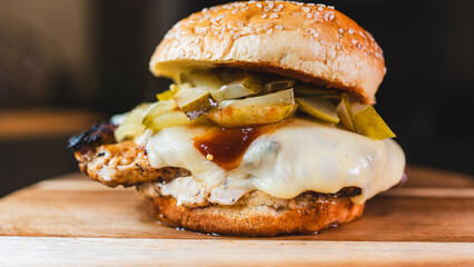 Succulent chicken breast burger on brioche bun with cheese, pickles, homemade mayo and barbecue sauce. Healthy, protein-rich meal perfect for fitness and balanced diets.