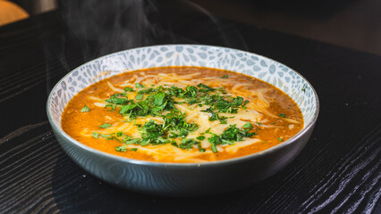 Thick vegetable soup with tender meat, melted cheese, and fresh parsley on top. Hearty, comforting, and perfect for cold days. Homemade and nutritious.