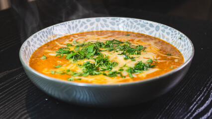 Thick vegetable soup with tender meat, melted cheese, and fresh parsley on top. Hearty, comforting, and perfect for cold days. Homemade and nutritious.