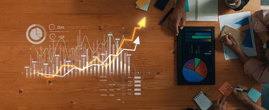 Business professionals collaborate on data analysis with charts and graphs on a wooden desk, featuring both digital devices and paper reports for effective strategy and decision-making. Scalp - Powered by Adobe
