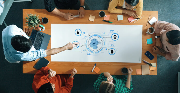A high-angle view of a diverse group of professionals collaborating on an artificial intelligence project with a digital mind map on the table, showcasing innovation and teamwork dynamics. Trope